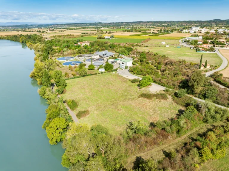 Vue aérienne par drone de la station d’épuration de Romans-sur-Isère et du terrain de l’extension, au bord de l’Isère