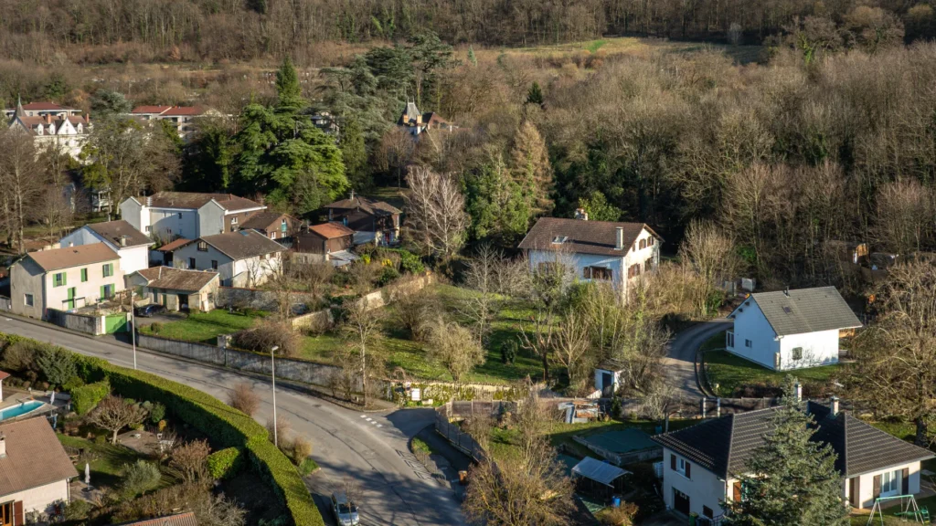 Le terrain de L’Écrin de Néméa à Poisat vu par drone, entre la rue, les maisons voisines et la colline boisée