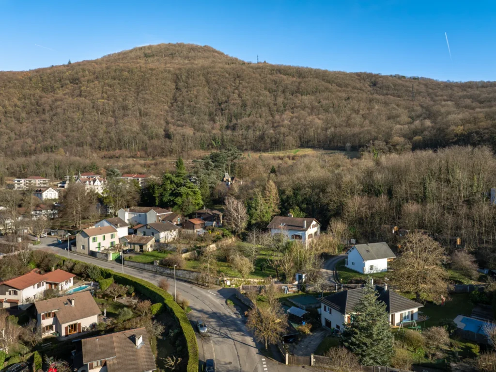 Vue de situation par drone du terrain de L’Écrin de Néméa à Poisat, au pied de la colline boisée