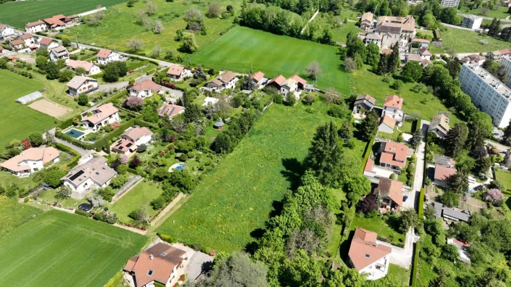 Vue aérienne oblique du pré du Domaine d’Anthyllis, entouré de maisons et de jardins à Voiron