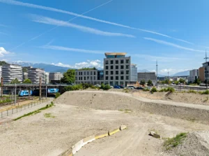 Terrain de Yello, sur l’îlot Arc-en-Ciel, place Nelson Mandela à Grenoble, vu par drone, avec les voies ferrées, les immeubles de la Presqu’île et les montagnes en arrière-plan
