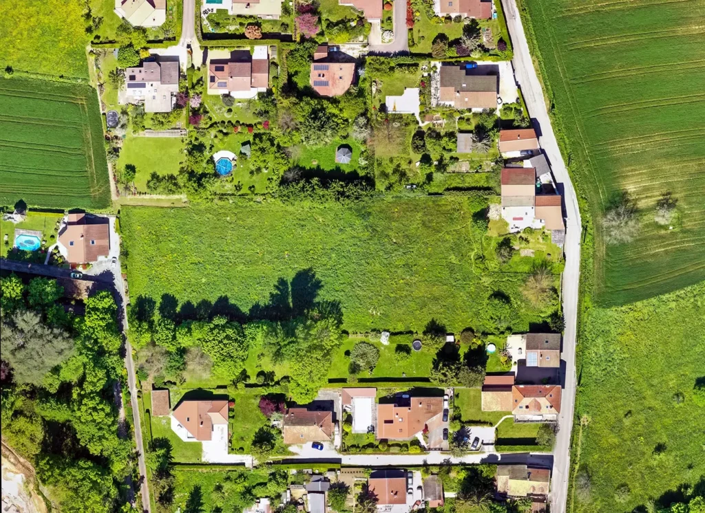 Avant : orthophoto par drone du terrain du Domaine d’Anthyllis à Voiron, un pré entouré de maisons et de jardins