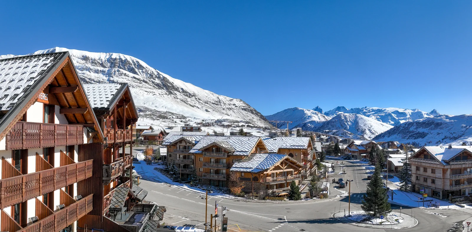 Vue prise par drone à la hauteur d’un futur étage de La Cristallière : le rond-point, les chalets et les sommets de l’Alpe d’Huez