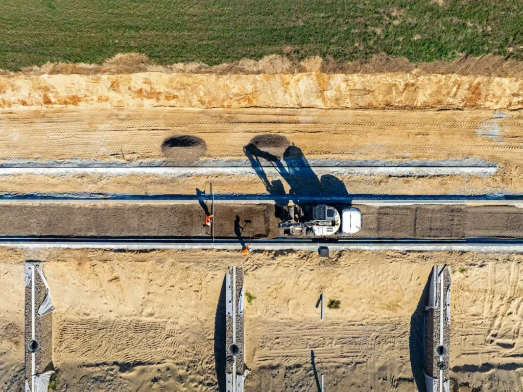 Ouvriers et pelle en train de réaliser la voirie du chantier Inspira à Sablons, vue à la verticale par drone